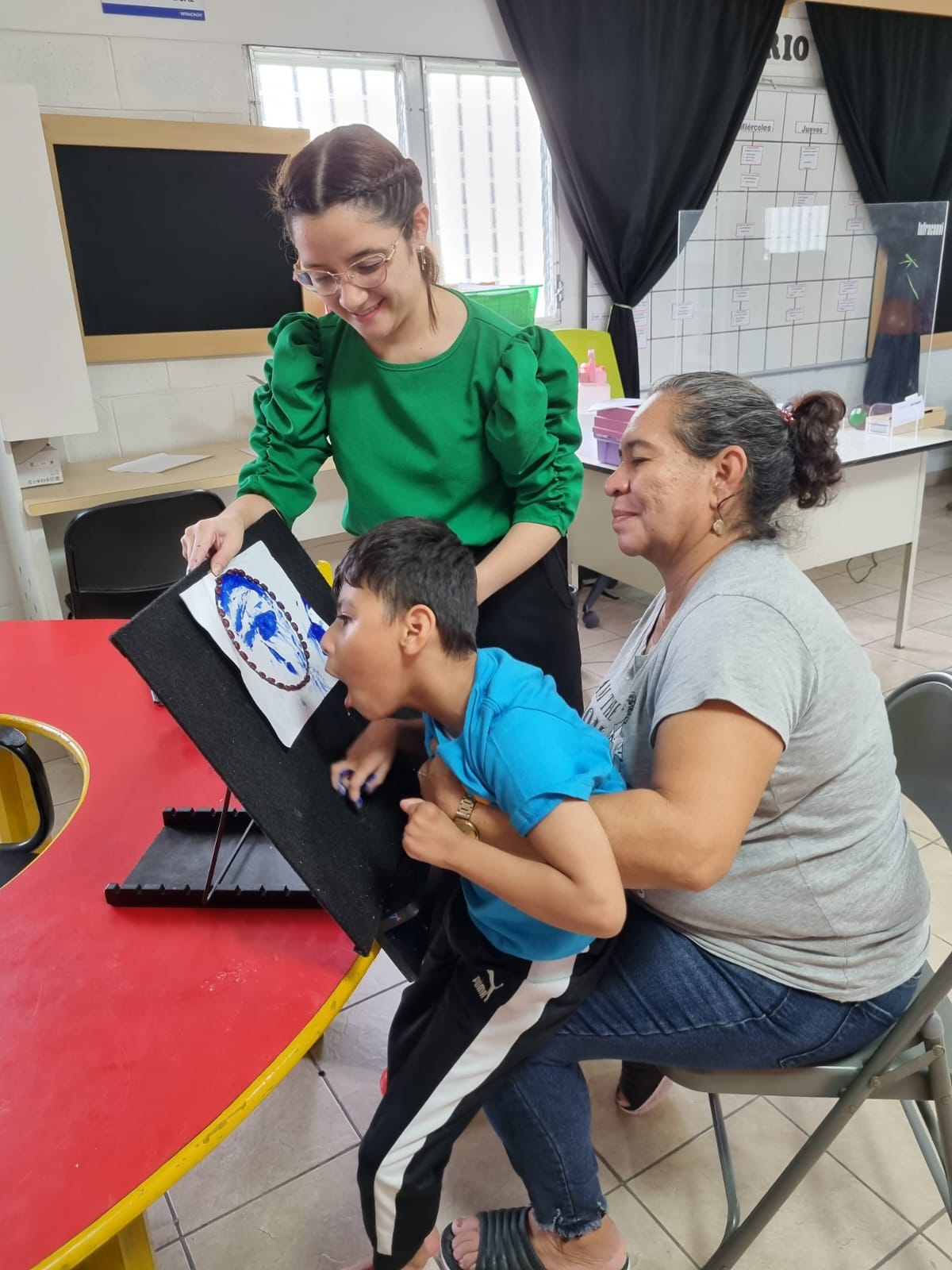 Tres personas participando en una actividad de estimulación visual, utilizando un objeto circular con patrones azules y blancos para captar la atención y desarrollar habilidades visuales.