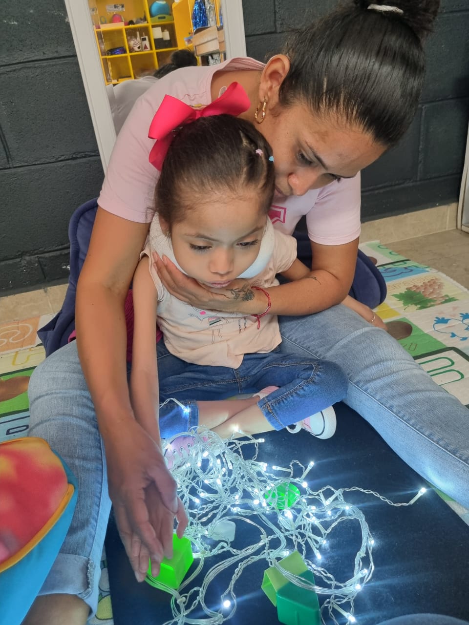 Niño participando en una actividad de estimulación visual, interactuando con luces brillantes y patrones para captar la atención y desarrollar habilidades visuales.