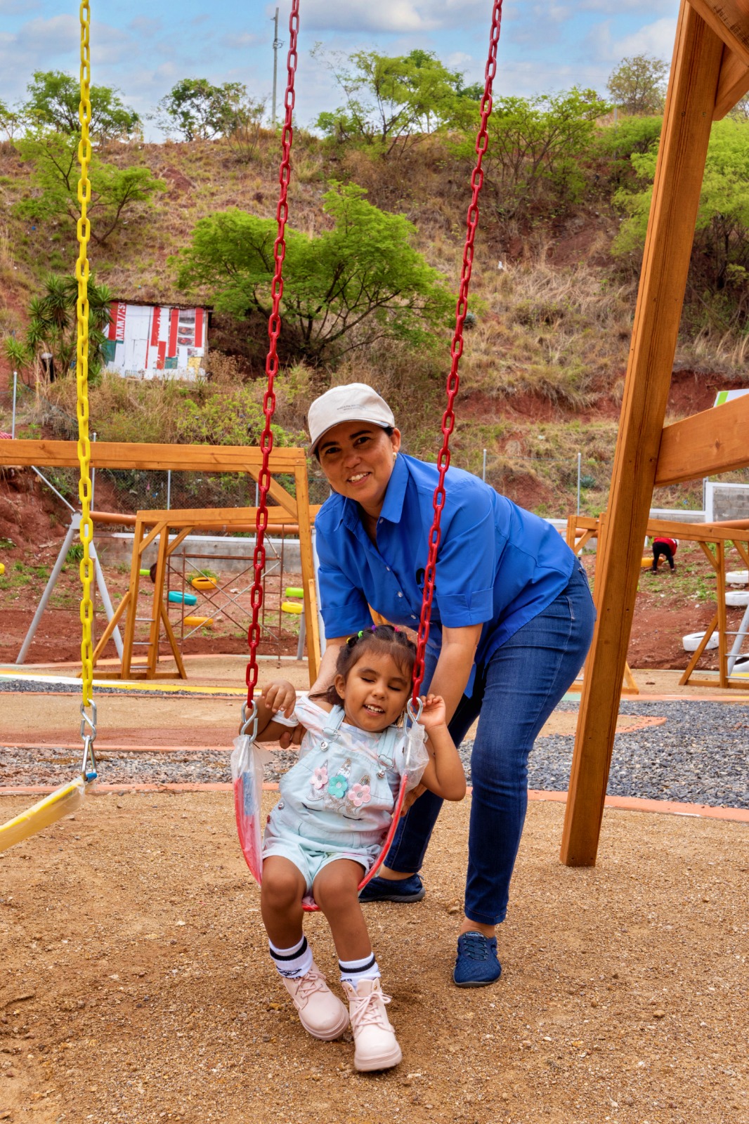 Niño disfrutando de actividades recreativas en un parque, siendo empujado en un columpio por un adulto. La escena muestra un entorno al aire libre con equipo de juego, destacando la importancia del ocio y la interacción social